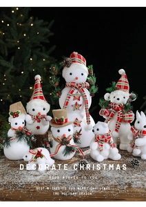 Close-up of white flocked snowman and reindeer decor on a snowy wooden table