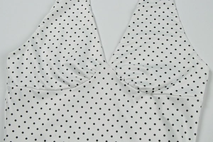 Close-up of a white polka dot halter top with V-neck and ruched chest detail