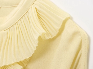 Detail view of the pale yellow chiffon top featuring ruffled pleated neckline design