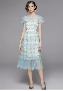 Détail de la broderie florale bleu clair sur les volants en tulle de la robe longue