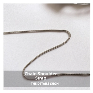 Macro detail of the silver metallic snake chain shoulder strap on white fabric