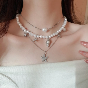 Detail of triple-layer seaside necklace featuring pearls, starfish and seashell pendants