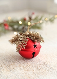 Macro view of a matte red Christmas bell with pine needles and star cutout details