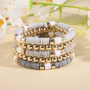 Détail de bracelets bohèmes superposés avec perles dorées et perles heishi en argile