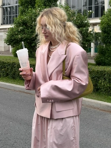 Detail of pink satin short blazer with flap pockets and elegant pearl necklace styling