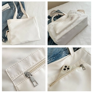 Detail view of large white tote bag with zippered front pocket and round logo patch