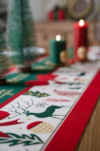 Detailed texture of red and green Christmas table runner with Merry Christmas gold embroidery