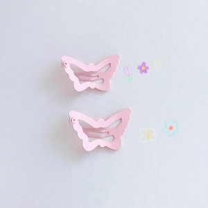 Close-up of two pink butterfly hair clips with a matte finish on a clean background