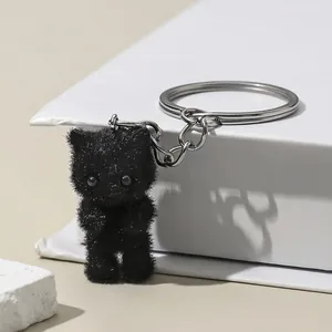 Close-up of cute black flocked cat keychain with glitter details and silver metal ring
