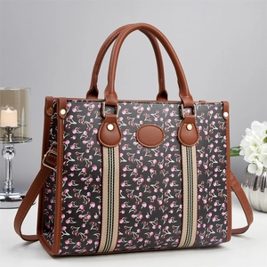 Elegant tote bag with cherry print and faux leather finish on indoor decor background