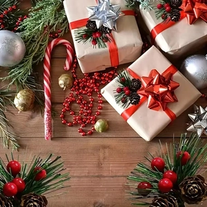 Mini Christmas gift boxes with pine needles, cones, berries and red ribbons on wood