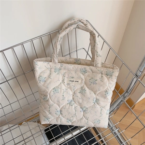 Détail du sac cabas matelassé avec motifs floraux et étiquette de marque tissée