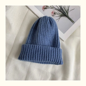 Detail of blue ribbed knit beanie on textured fabric with warm floral background decor