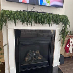 Close-up of artificial pine garland draped over a white fireplace for Christmas decor