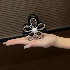 Detail of sunflower hair claw with black resin petals, silver rhinestones and a white pearl