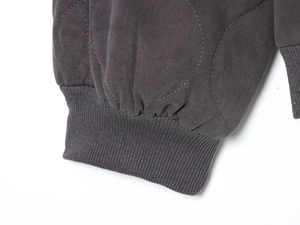 Detail of dark grey quilted fabric and elastic ribbed cuffs on a loose bomber jacket