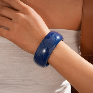 Detail of wide navy blue resin bangle with glossy finish worn on a woman's wrist