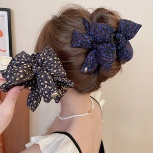 Detail showing bow hair claw clip with floral pattern and gold metal LOVE tag on hair