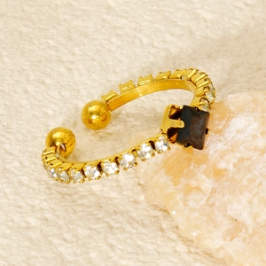 Macro shot of gold-plated ring with square black gemstone and small white crystals