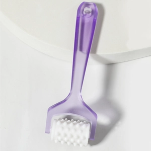 Close-up of handheld manual roller massager with purple handle on a white platform
