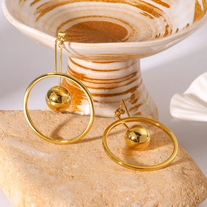 Minimalist gold stainless steel hoop earrings with sphere pendant on beige stone