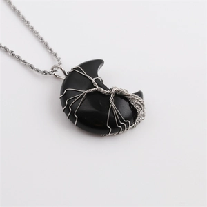 Macro view of black agate moon pendant with silver tree of life wire wrap and twist chain