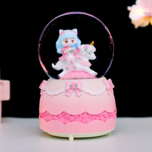 Macro shot of a pink unicorn music box featuring a girl inside a crystal ball globe