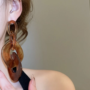 Detailed view of large tortoiseshell amber acrylic chain link earrings on a model