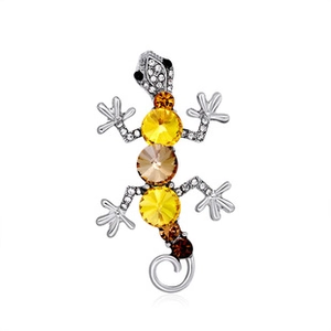Detailed macro view of silver gecko brooch with yellow crystals and pavé rhinestones