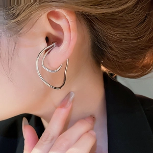 Close-up of a silver irregular twisted double-layer metal ear cuff worn on the earlobe