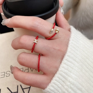 Close-up of gold and red enamel stackable rings with H-letter and nail design details