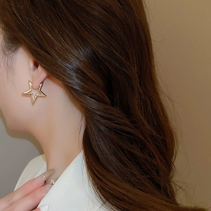 Detail of elegant gold hollow star earrings worn by model for a minimalist chic style