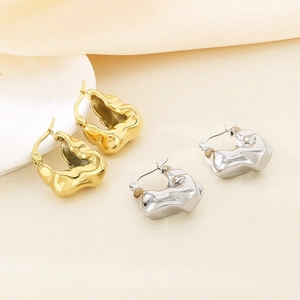 Modern 18K gold and silver irregular lava earrings on elegant silk background