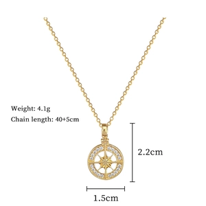 Detailed view of a gold starburst compass pendant with measurements and crystal accents