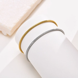 Minimalist stainless steel snake bone bracelets in gold and silver on white display