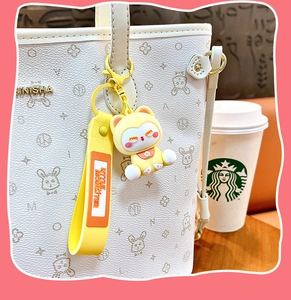 Détail d'un mignon porte-clés chat de dessin animé jaune attaché à un sac à main blanc