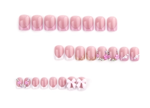 Detail of pink French press-on nails with glitter, rhinestones, flowers and bows