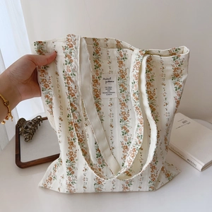 Detailed view of spacious floral cotton tote bag with orange flower print and cloth label