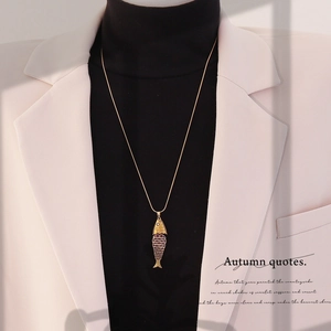 Golden koi fish pendant necklace with purple scales worn on a black turtleneck sweater