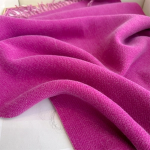 Detailed close-up of fuchsia cashmere blend scarf fabric showing soft wool texture and fringe