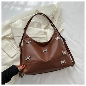 Dettaglio borsa tote in pelle marrone con eleganti decorazioni a farfalla argentate