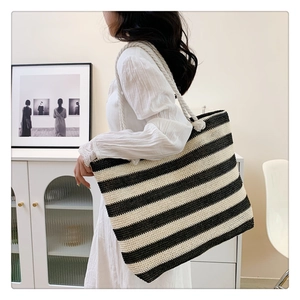 Detail of large woven straw tote bag featuring black and white stripes and sturdy rope handles