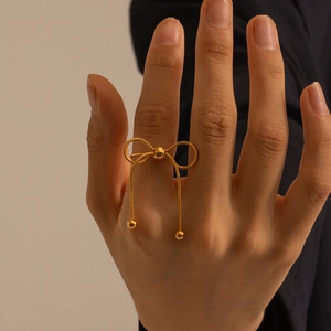 Detailed view of adjustable golden butterfly ring with dangling chains on model's hand