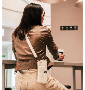 Detail of off-white mesh water bottle pouch with adjustable strap and text logo