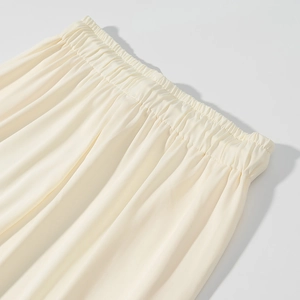 Dettaglio di pantaloni in maglia color crema con vita elastica e consistenza setosa