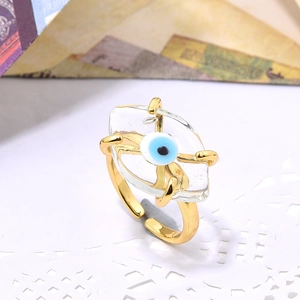 Macro detail of gold-plated open ring featuring a blue evil eye bead and clear resin stone