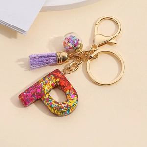 Detail of glitter letter P resin keychain with purple tassel and gold lobster clasp