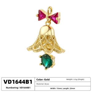 Detail view of gold brass Christmas bell pendant with red bow and emerald crystal