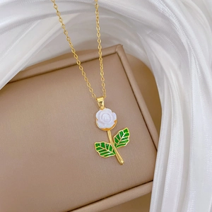 Close-up of golden necklace with a white rose pendant on a beige jewelry box