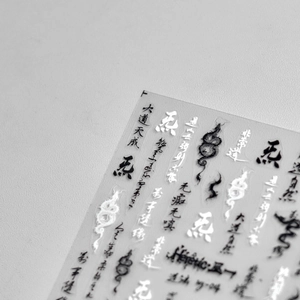 Macro detail of Japanese nail stickers featuring black ink calligraphy and dragon totems
